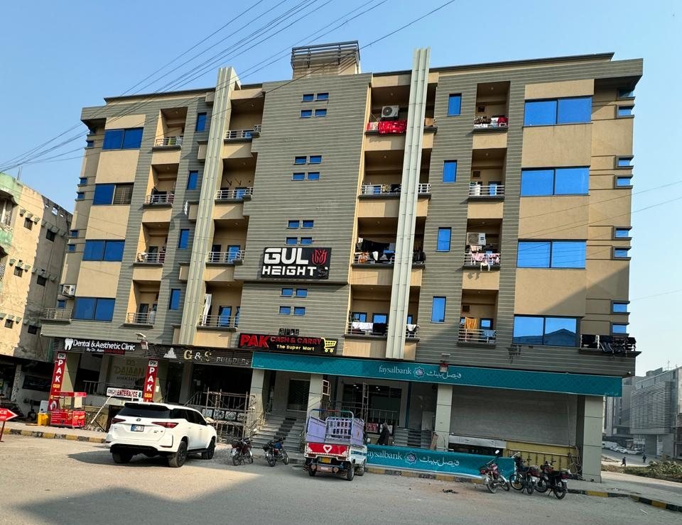 Gul Heights 1 photographed from Main Markaz D-17 &mdash; six floors above the street-level shops, the G & S Builders frontage among them
