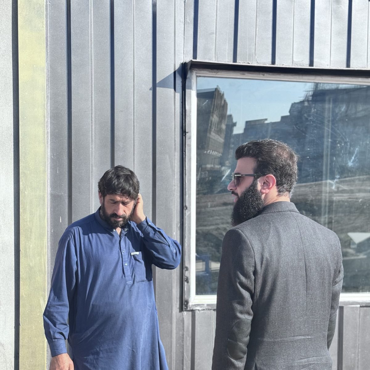On the Gul Heights 2 site in Islamabad — the building under construction reflected in the site-office glass